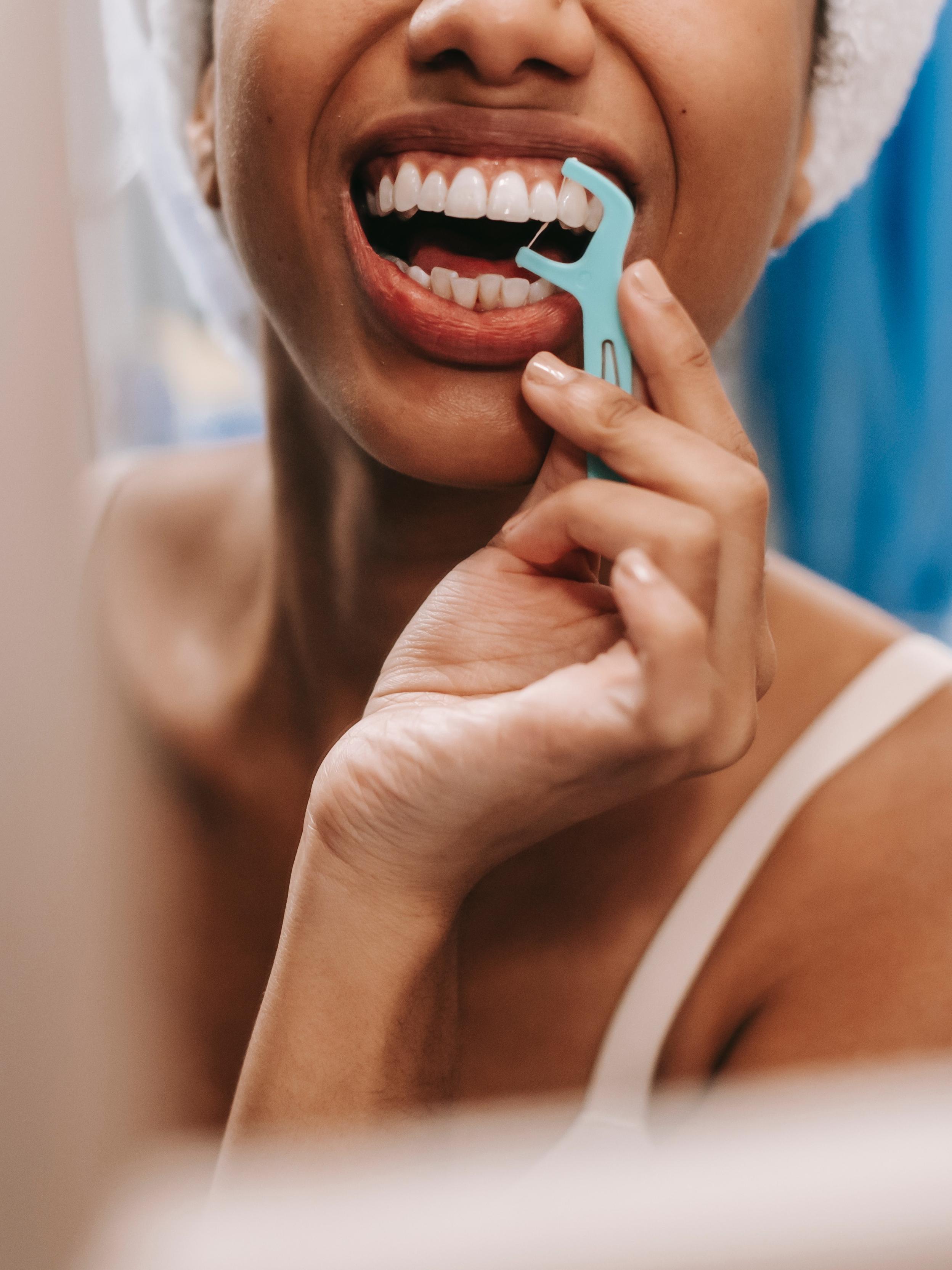 woman flossing her teeth with a floss pick