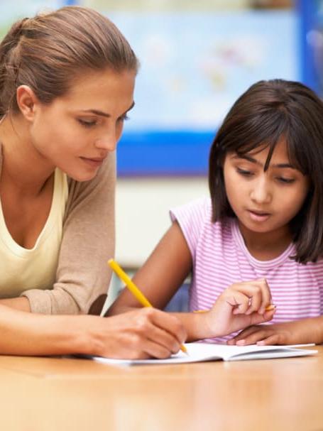 woman helping girl with schoolwork