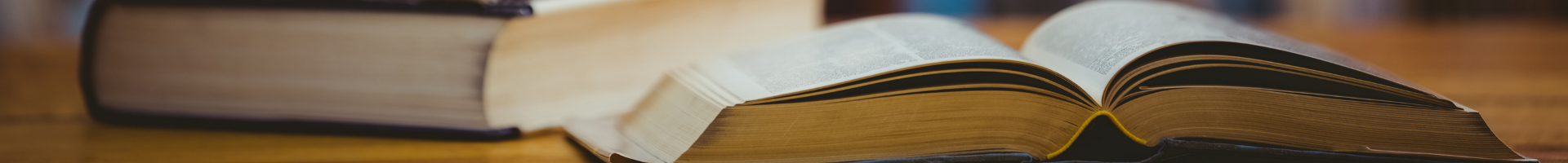 photograph of an open book and a stack of books on a table